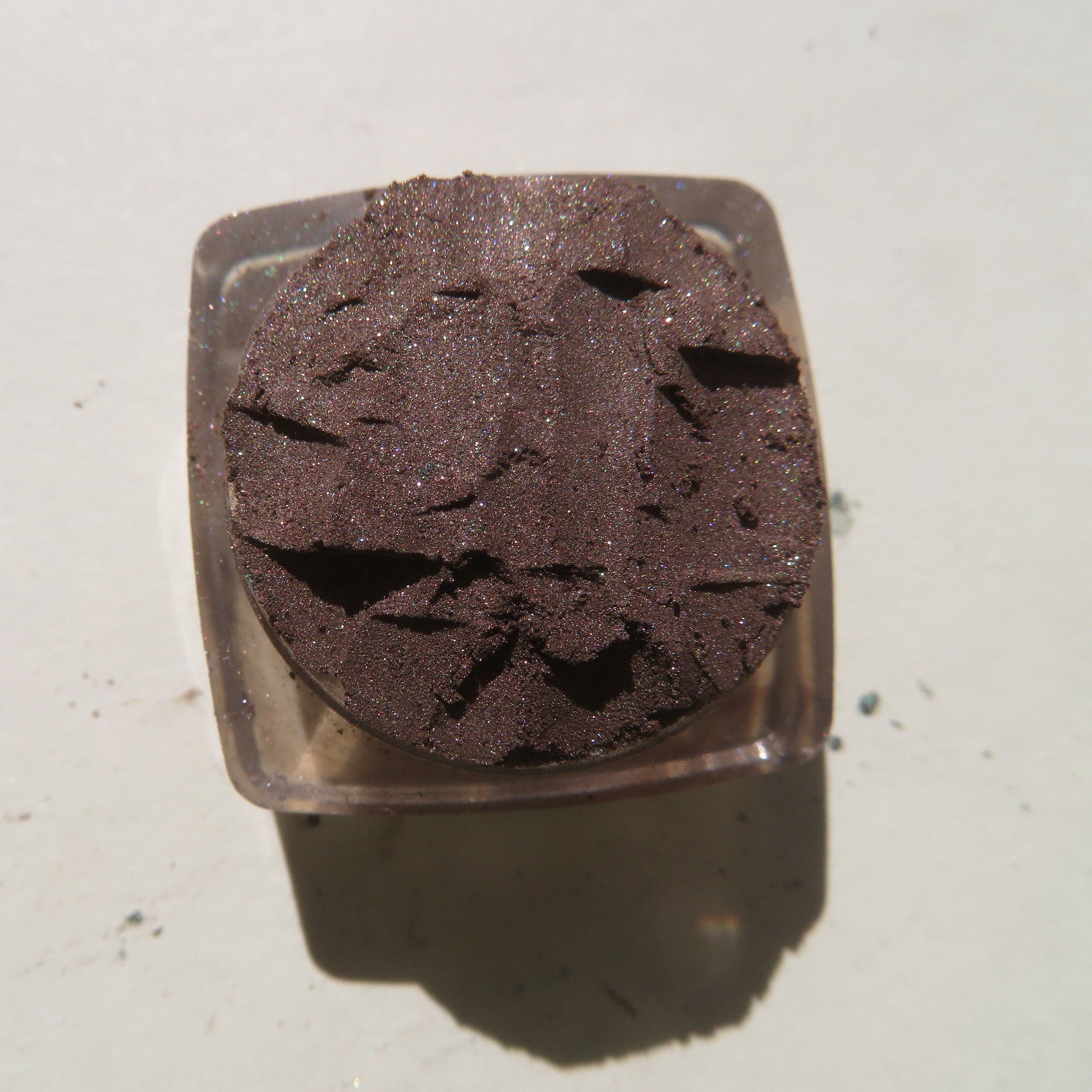 Open jar of Trolls loose mineral eyeshadow showing rich dark brown shimmer pigment with vegan label