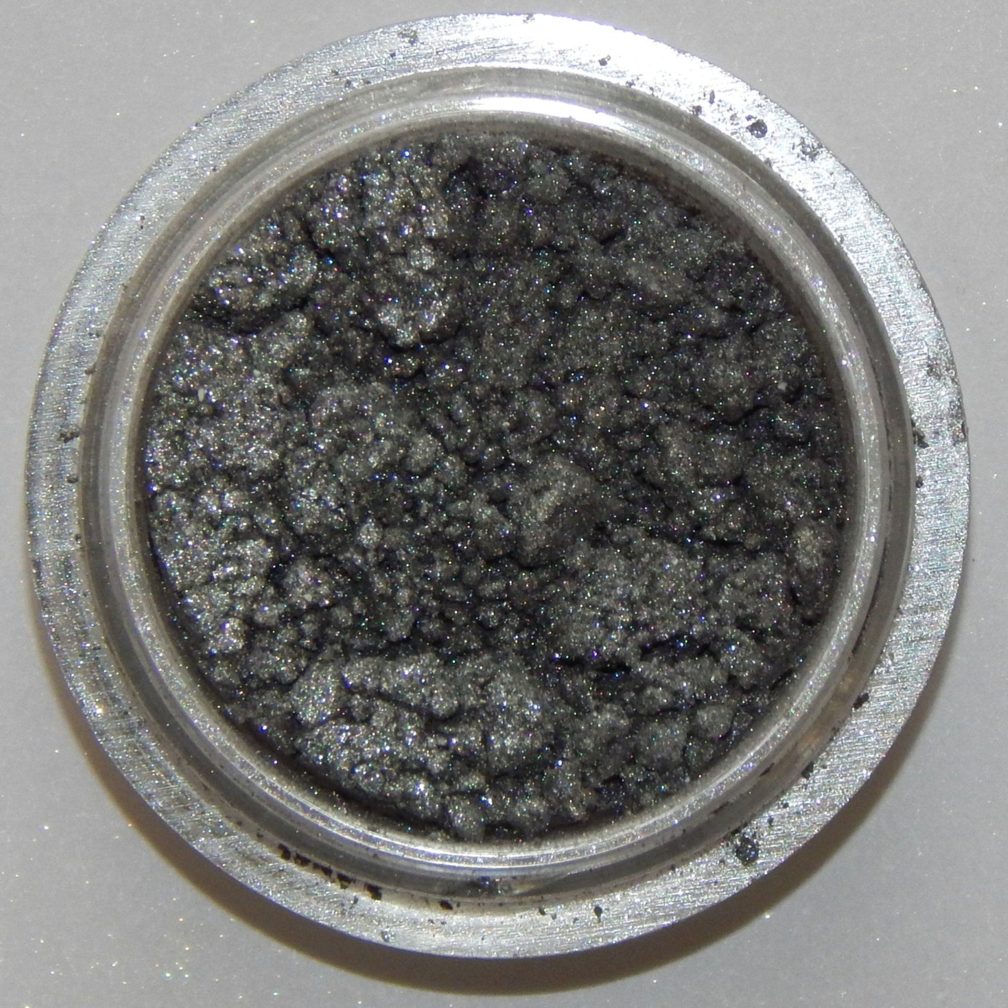 Close-up of Arc Angel Mineral Eye Shadow showing shimmering silver and blue swirls in compact pan