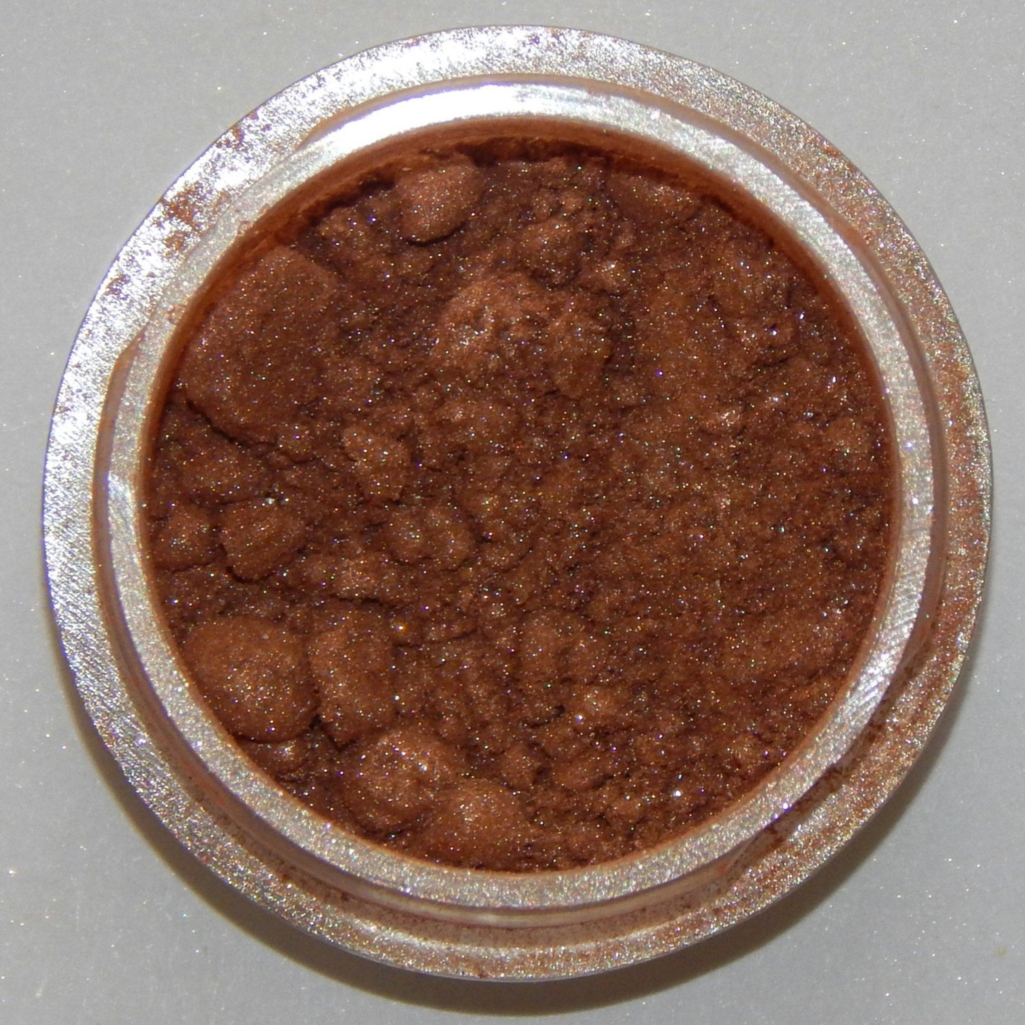 Close-up of warm amber mineral eyeshadow with soft shimmer finish in compact case