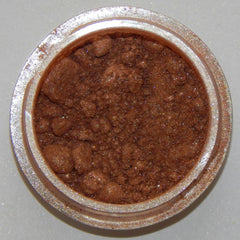 Close-up of warm amber mineral eyeshadow with soft shimmer finish in compact case