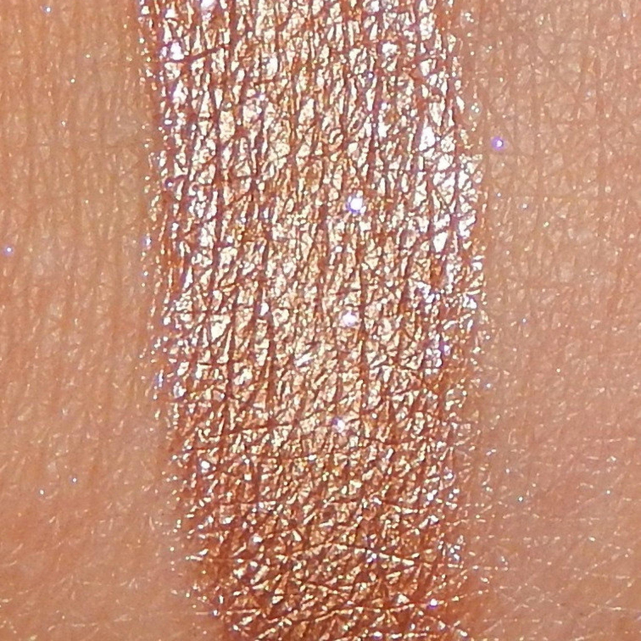 Side view of amber mineral eyeshadow pan showing soft shimmer texture and warm golden undertones