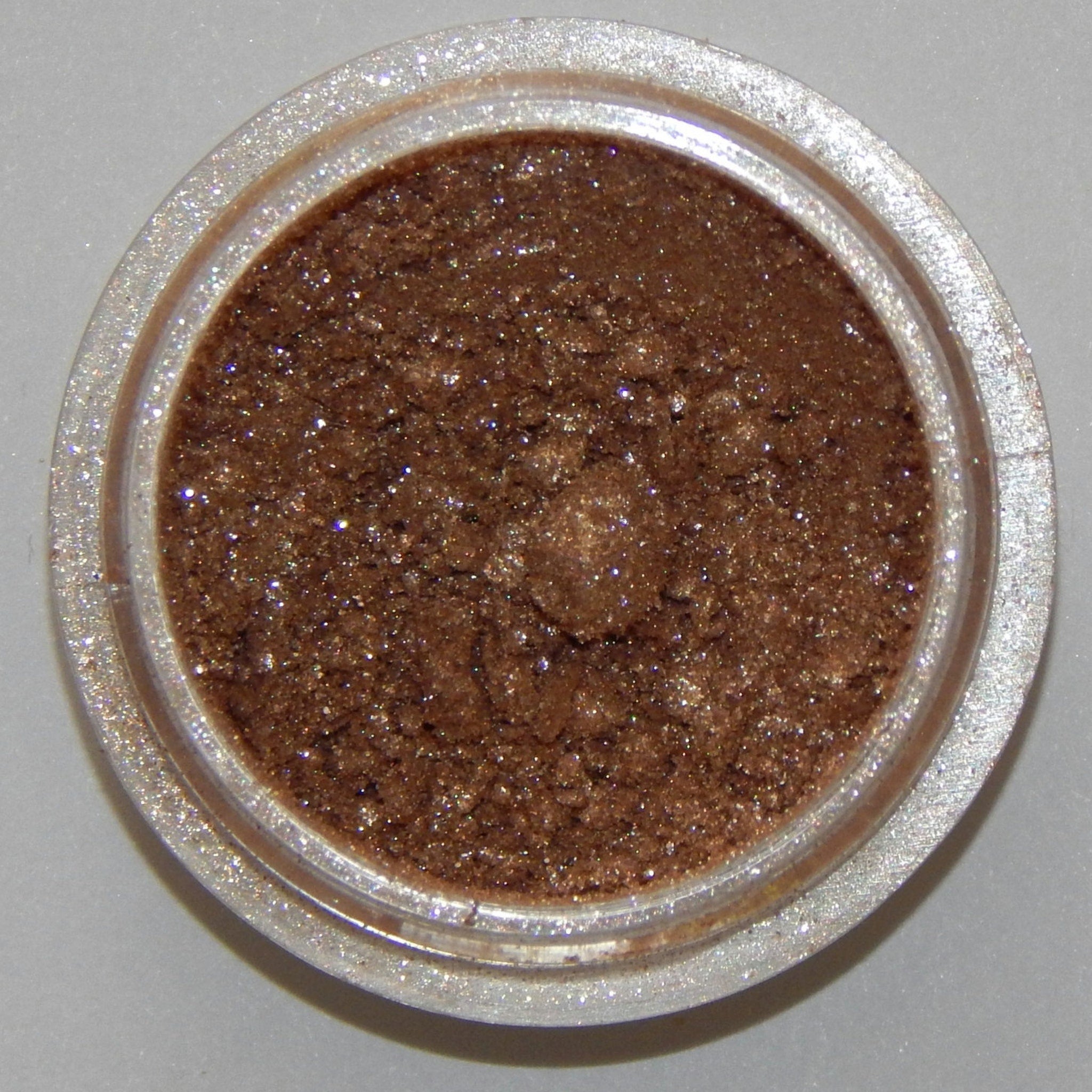 Close-up of frothy mineral eyeshadow pan showing soft, blendable powder texture in a neutral shade
