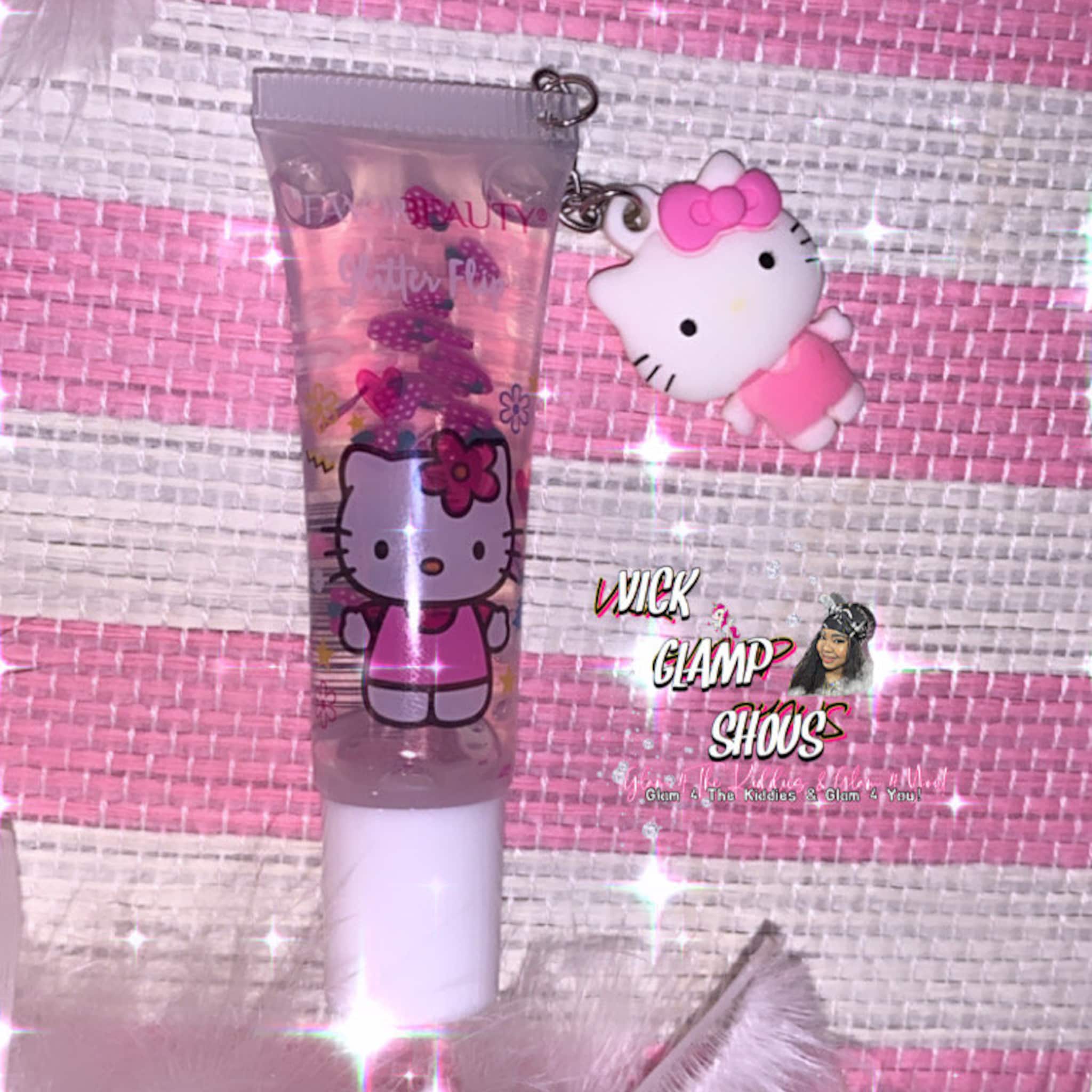 Lip gloss tube with Hello Kitty charm, clear liquid, pink glitter, and white applicator