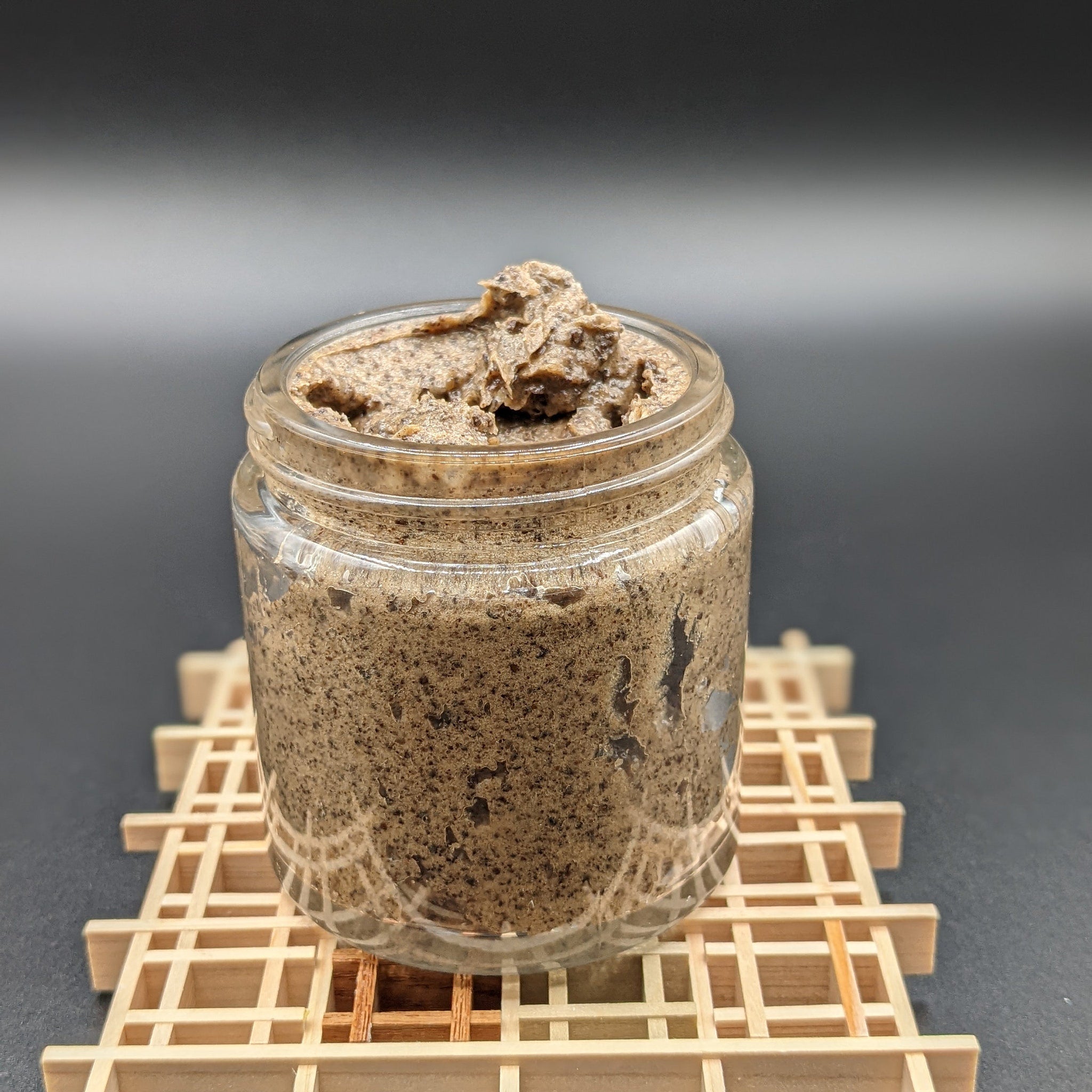Jar of brown paste in a clear glass jar on a wooden lattice, studio shot
