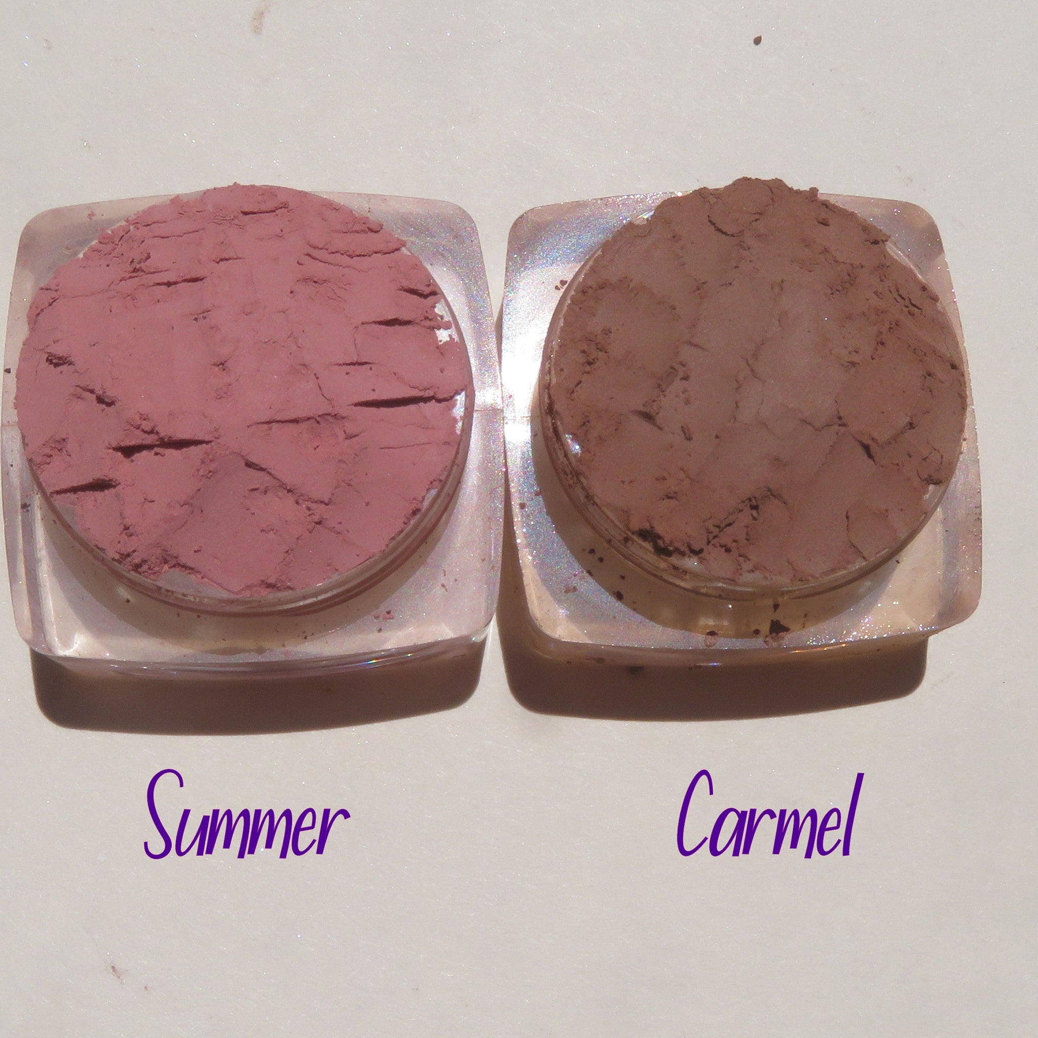 Close-up of four loose mineral eyeshadows in matte taupe, shimmer champagne, satin mauve, and metallic bronze shades