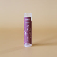 Lip balm tube with purple label, white text, and clear cap for application
