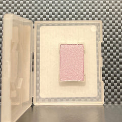 Close-up of fingertips applying shimmering dusty lilac mineral eye shadow to eyelid with soft blending brush