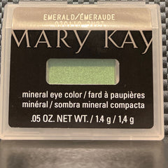 Side angle view of shimmering emerald mineral eye shadow in compact, showcasing reflective green sparkle and smooth texture
