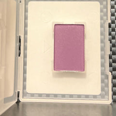 Close-up of fingertips applying shimmering purple iris mineral eye shadow to eyelid crease