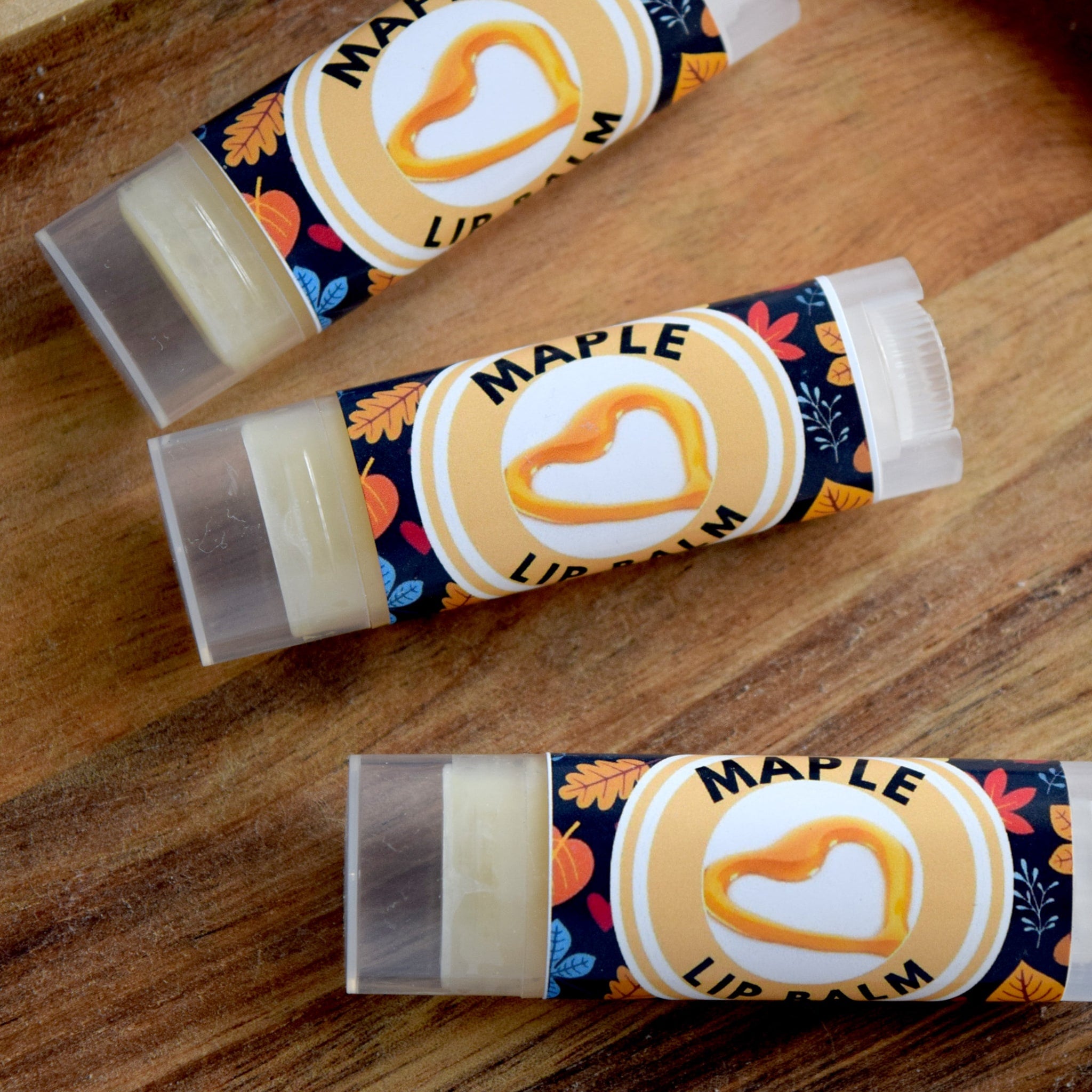 Maple lip balm tubes with clear plastic casing, patterned label, and maple heart graphic