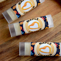 Maple lip balm tubes with clear plastic casing, patterned label, and maple heart graphic