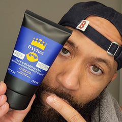 Face and beard wash tube with blue and black color, "Oxylux" brand, held by a person