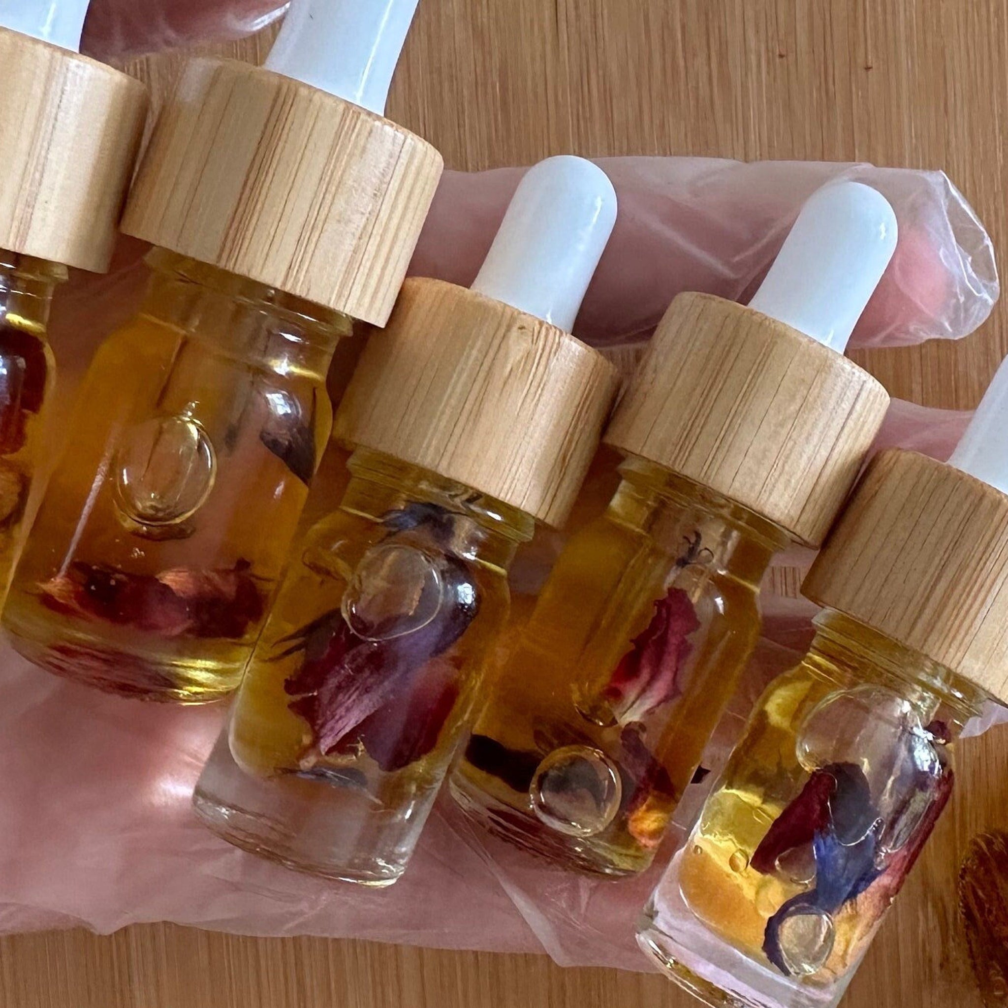 Essential oil bottles with wooden lids, clear glass, and floral inclusions