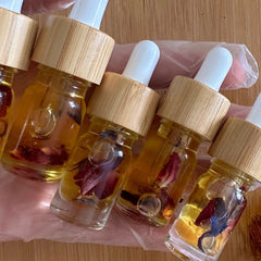 Essential oil bottles with wooden lids, clear glass, and floral inclusions