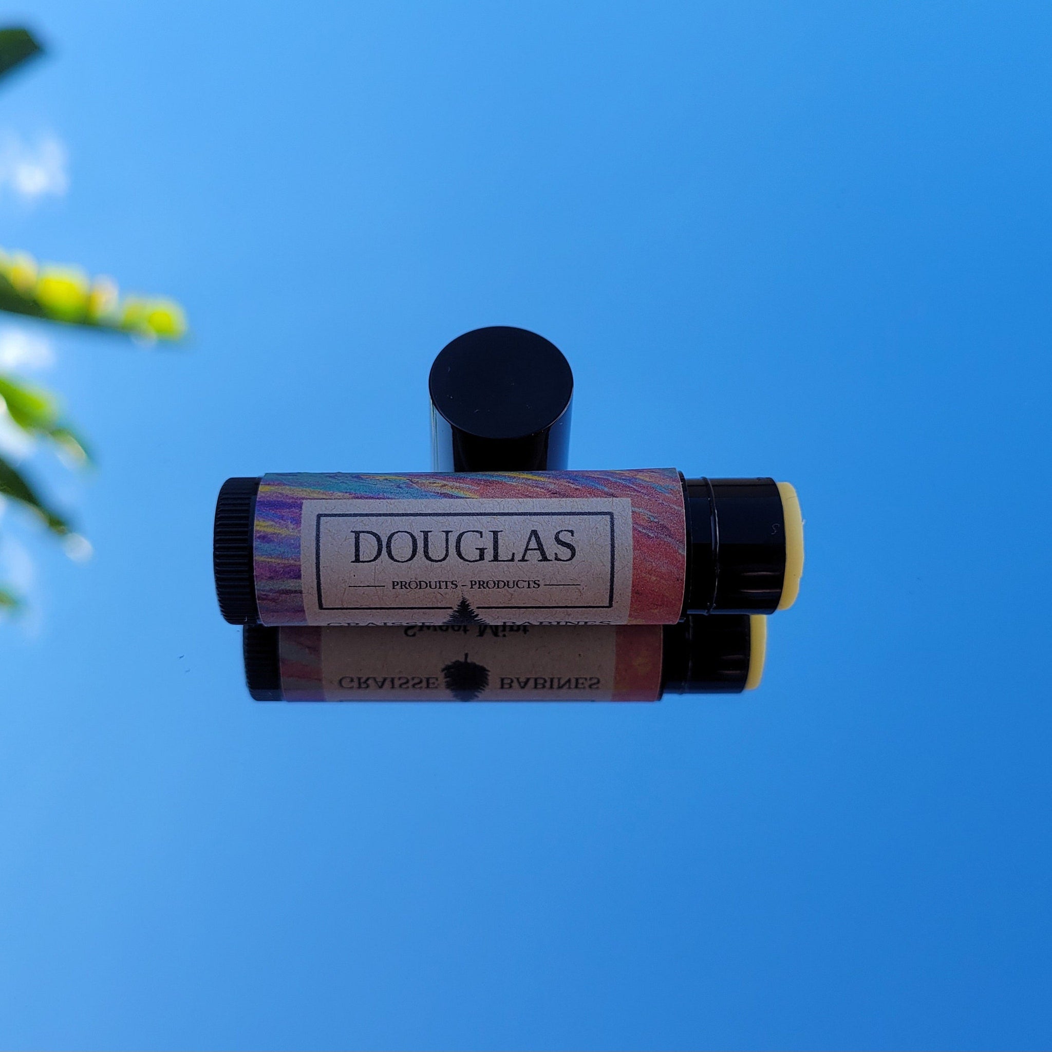 Lip balm tube with black cap, colorful patterned label, and DOUGLAS branding