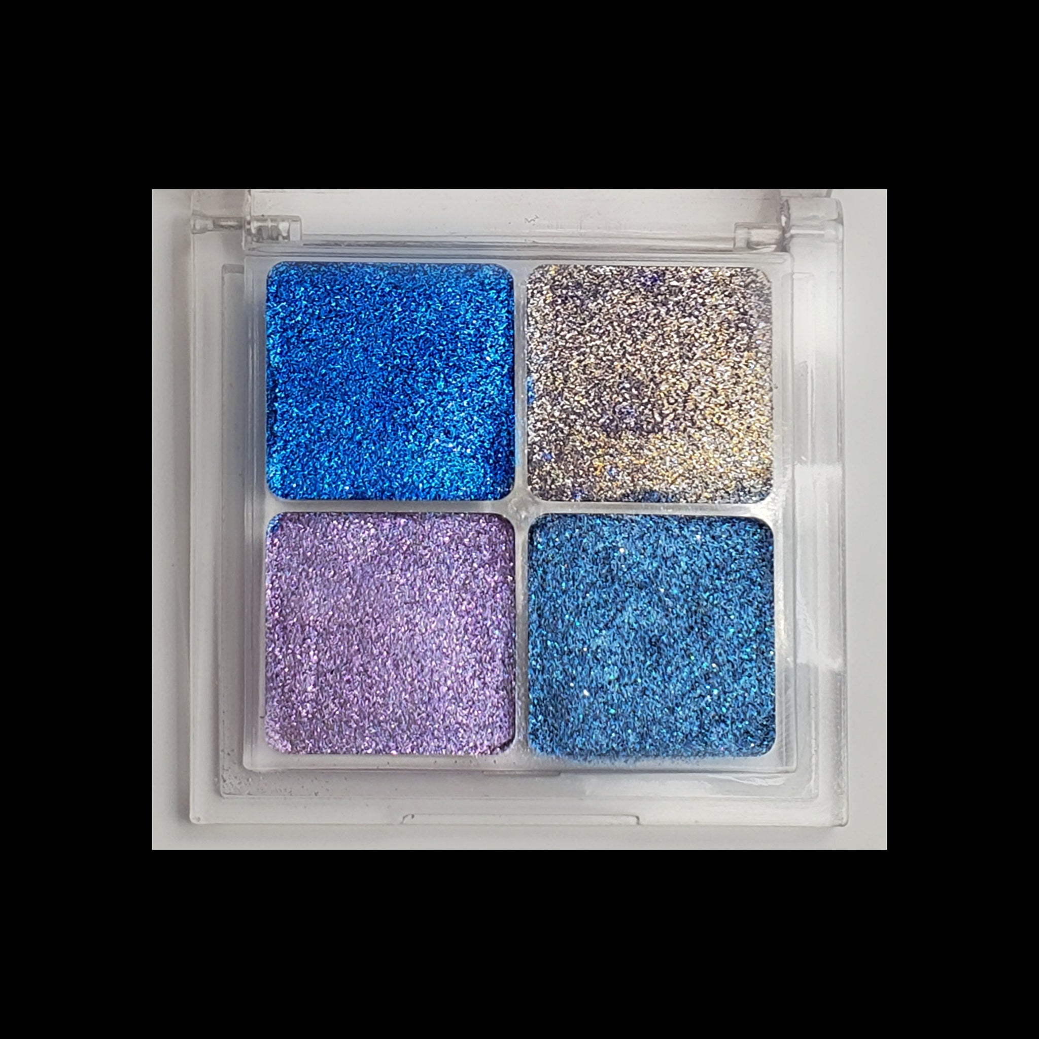 Open duochrome eyeshadow palette displaying eight shimmering shades in metallic and iridescent finishes