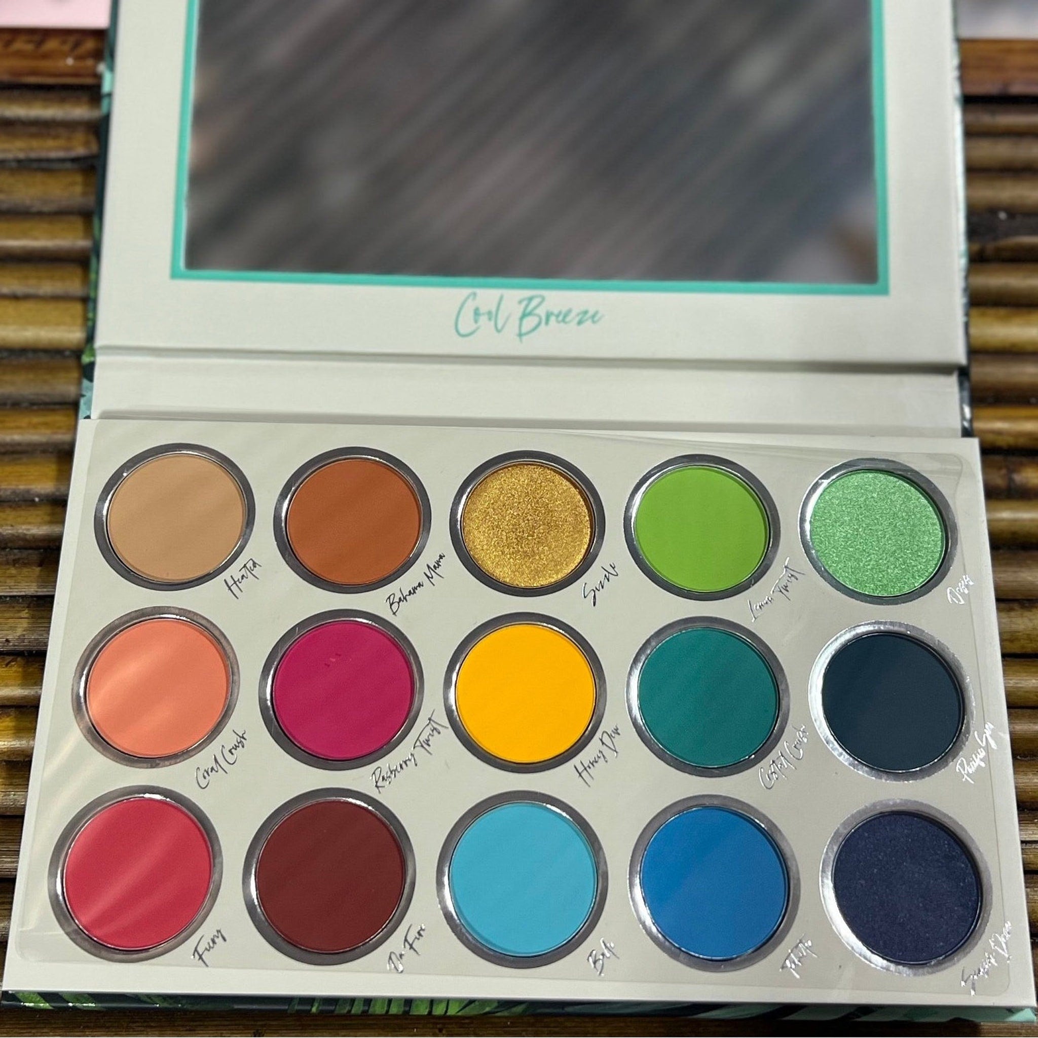 Eyeshadow palette with multiple colors, including gold, green, and blue, with "Cool Breeze" text on the lid.