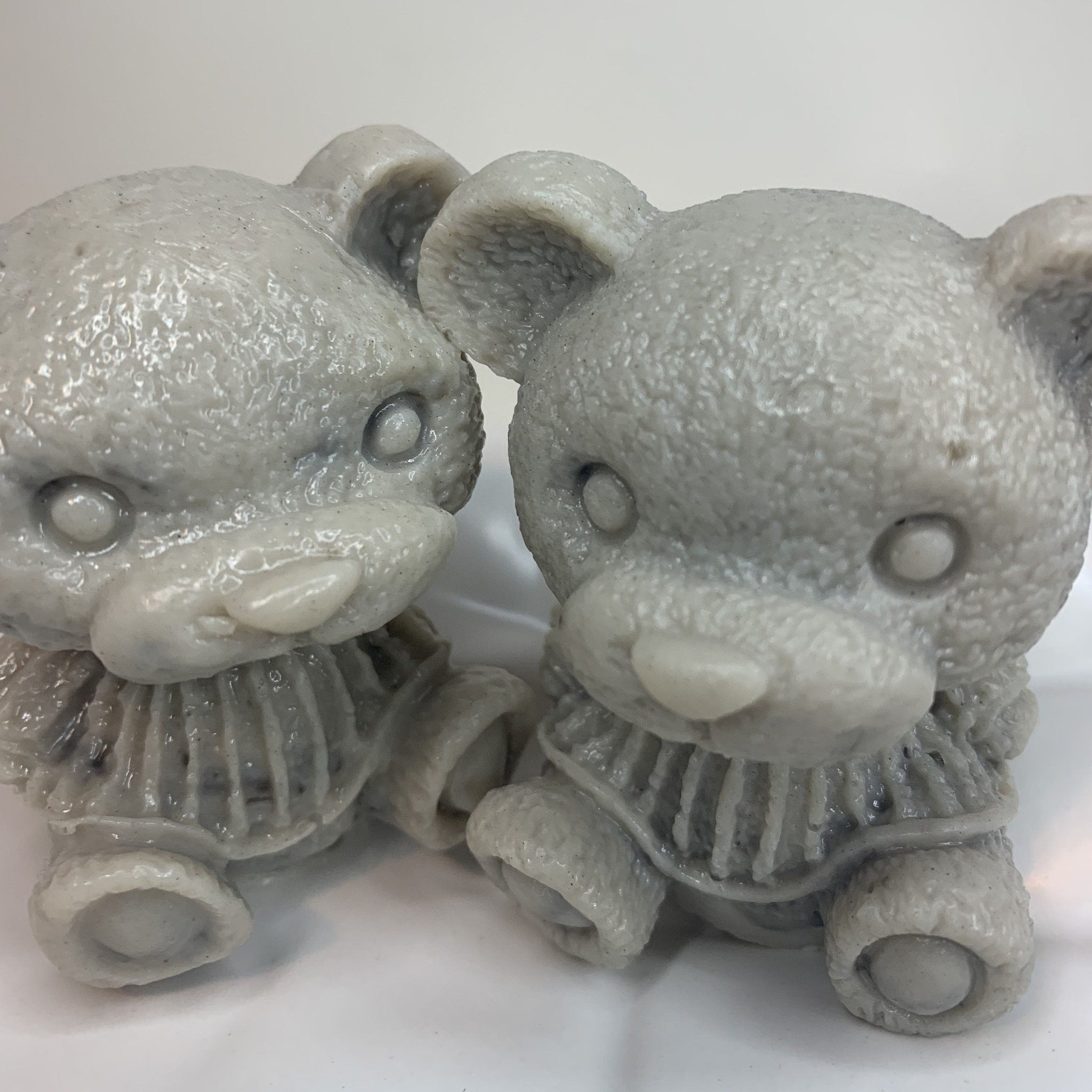 Gray teddy bear figurines with textured surface and detailed clothing style