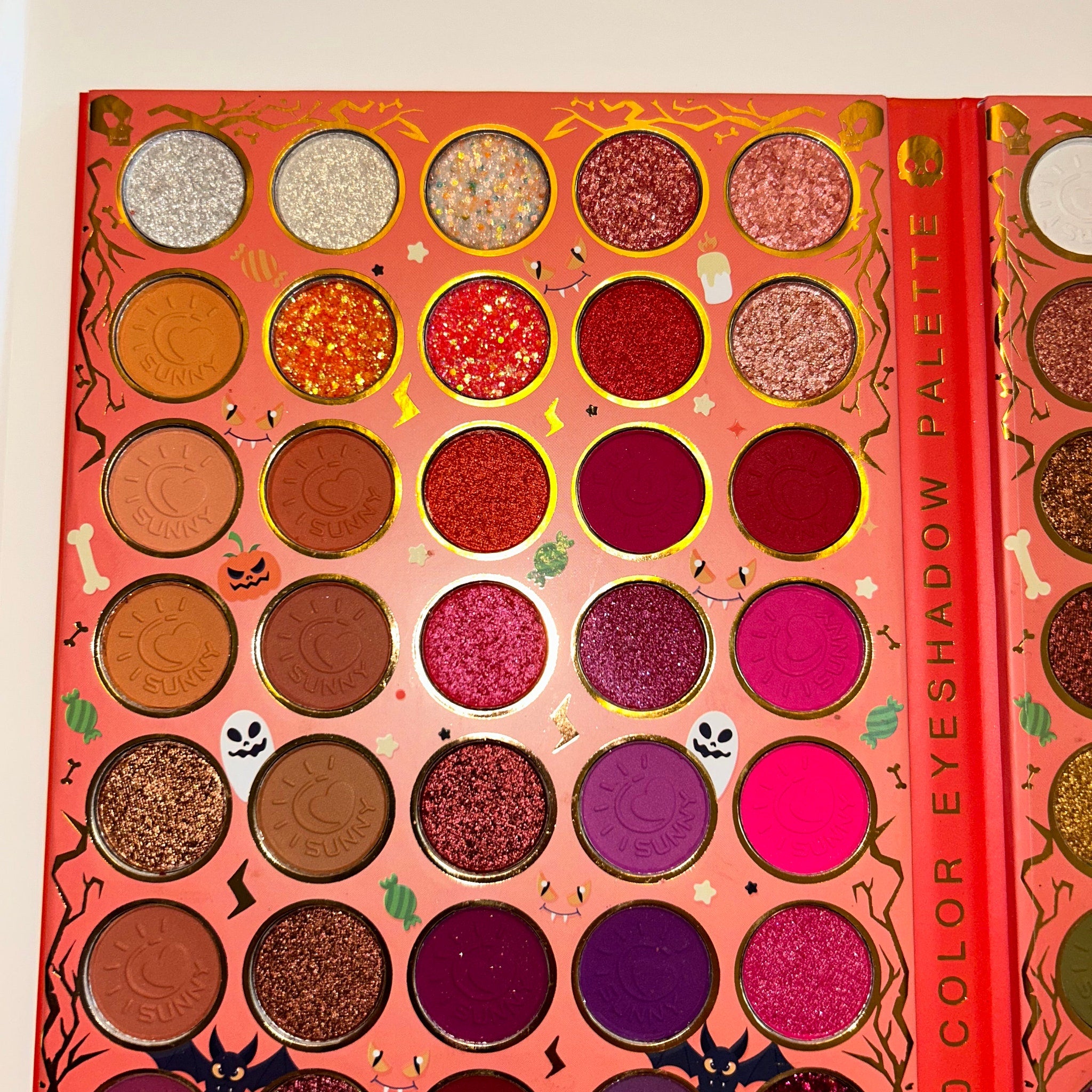 Side view of Halloween eye shadow palette showcasing vibrant orange, black, and purple matte shades in rectangular pans