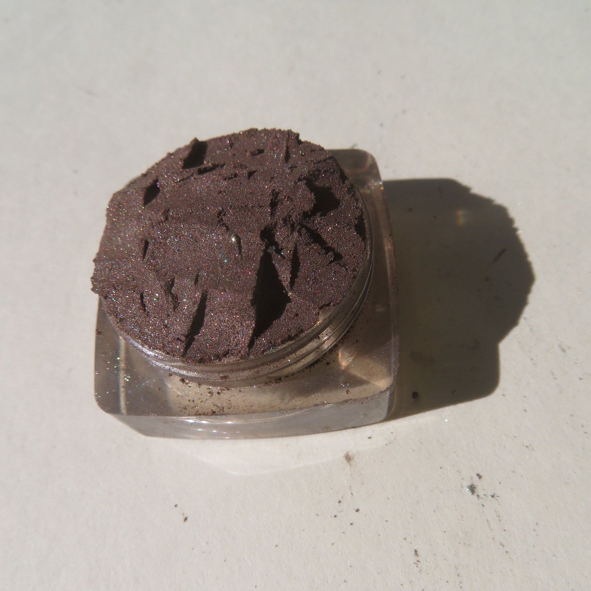 Hand applying rich dark brown shimmer vegan loose mineral eyeshadow with a brush for a smoky eye look
