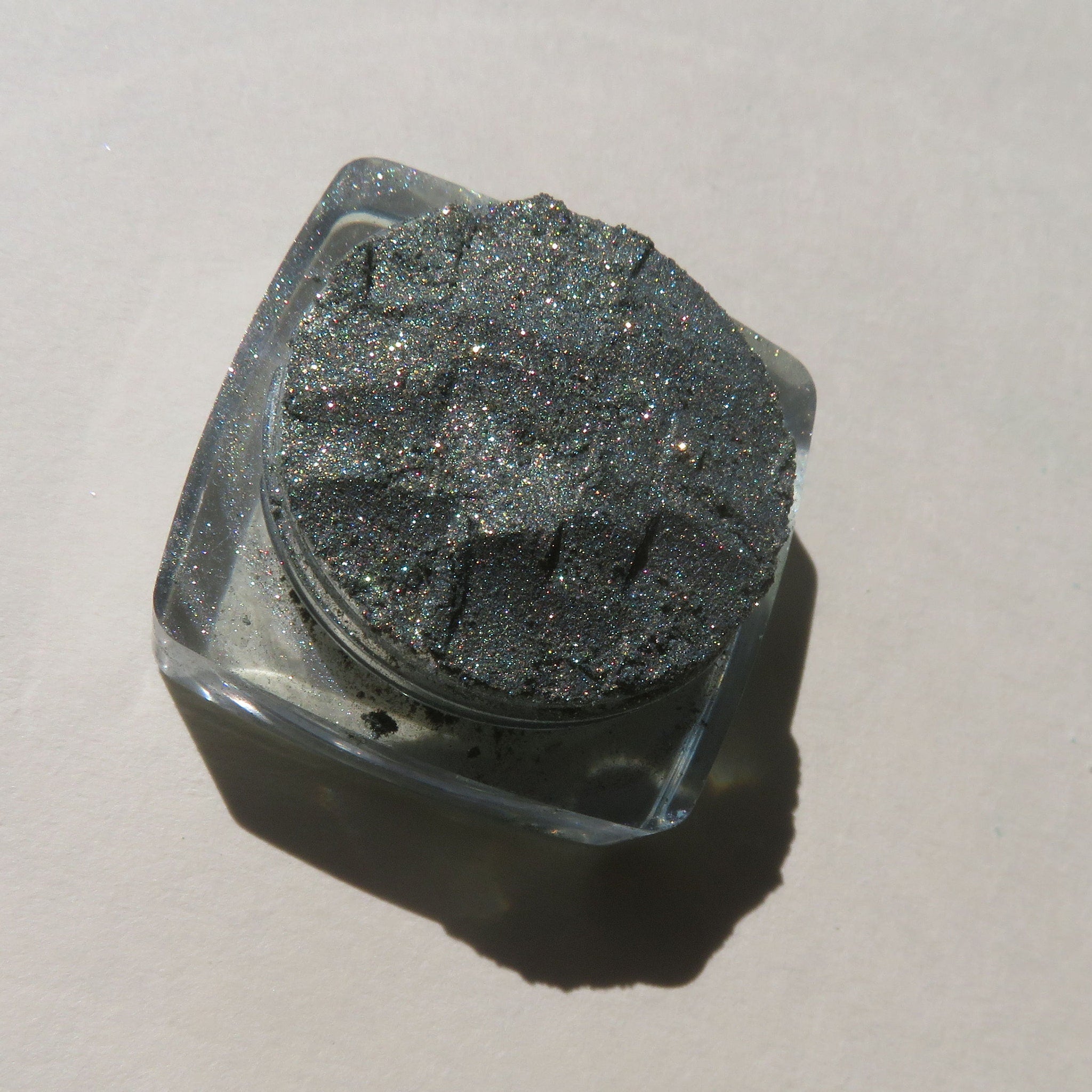 Glitter eyeshadow powder in gray with sparkling particles, in clear square container
