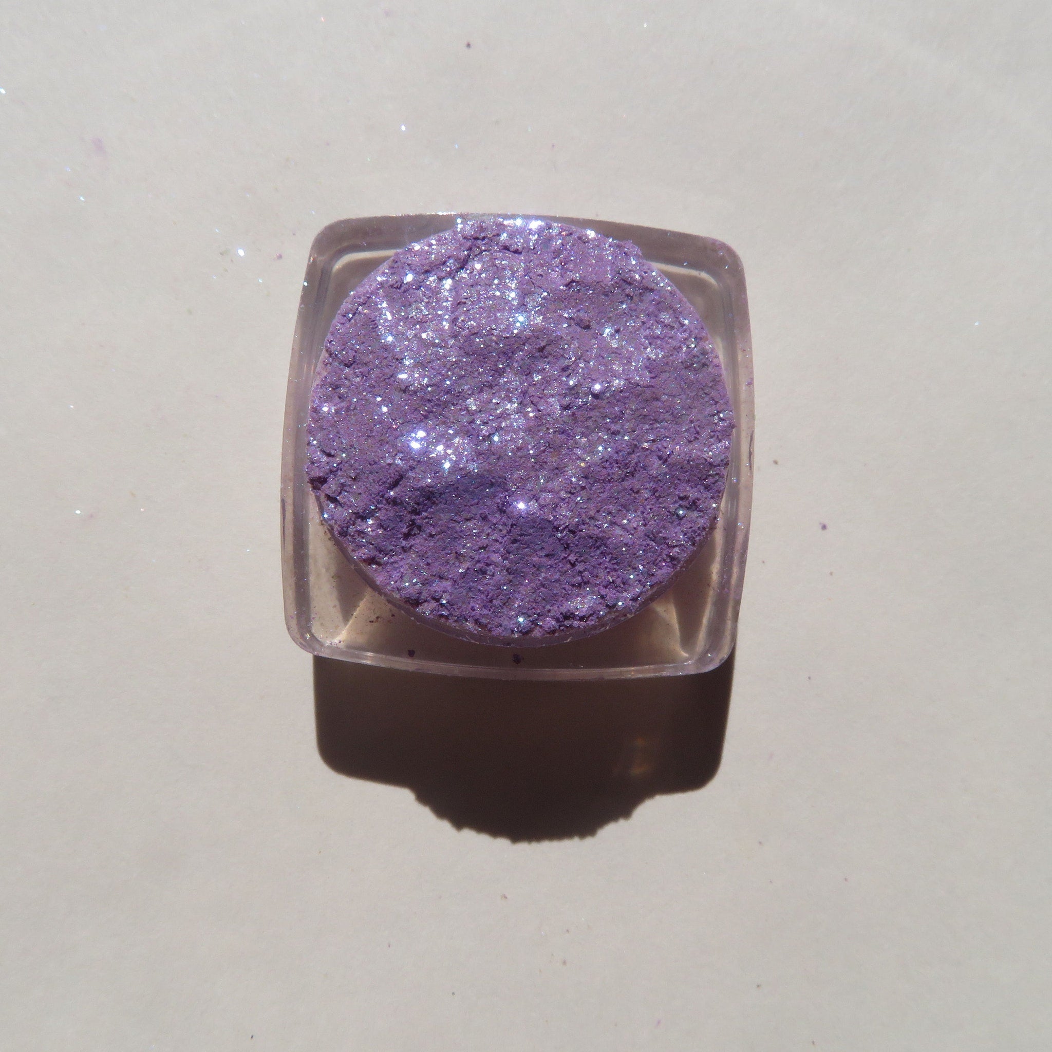 Close-up of sparkling violet and blue mineral eye shadow with glitter particles catching light