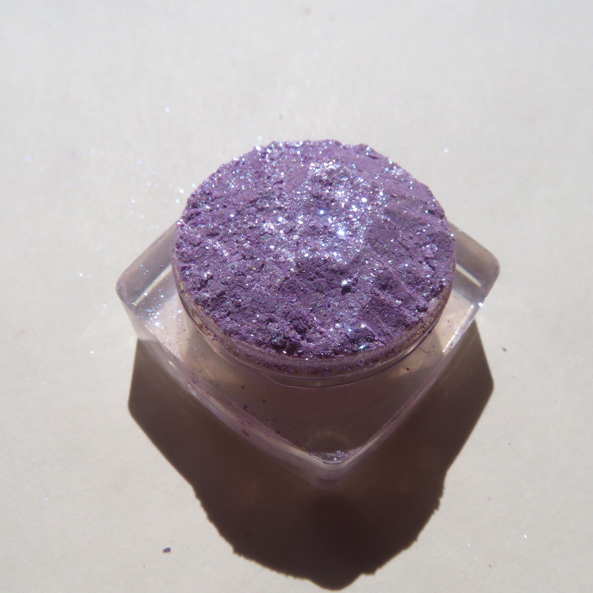 Side view of Winter Violets shimmer eye shadow palette showing sparkling purple and blue glitter texture