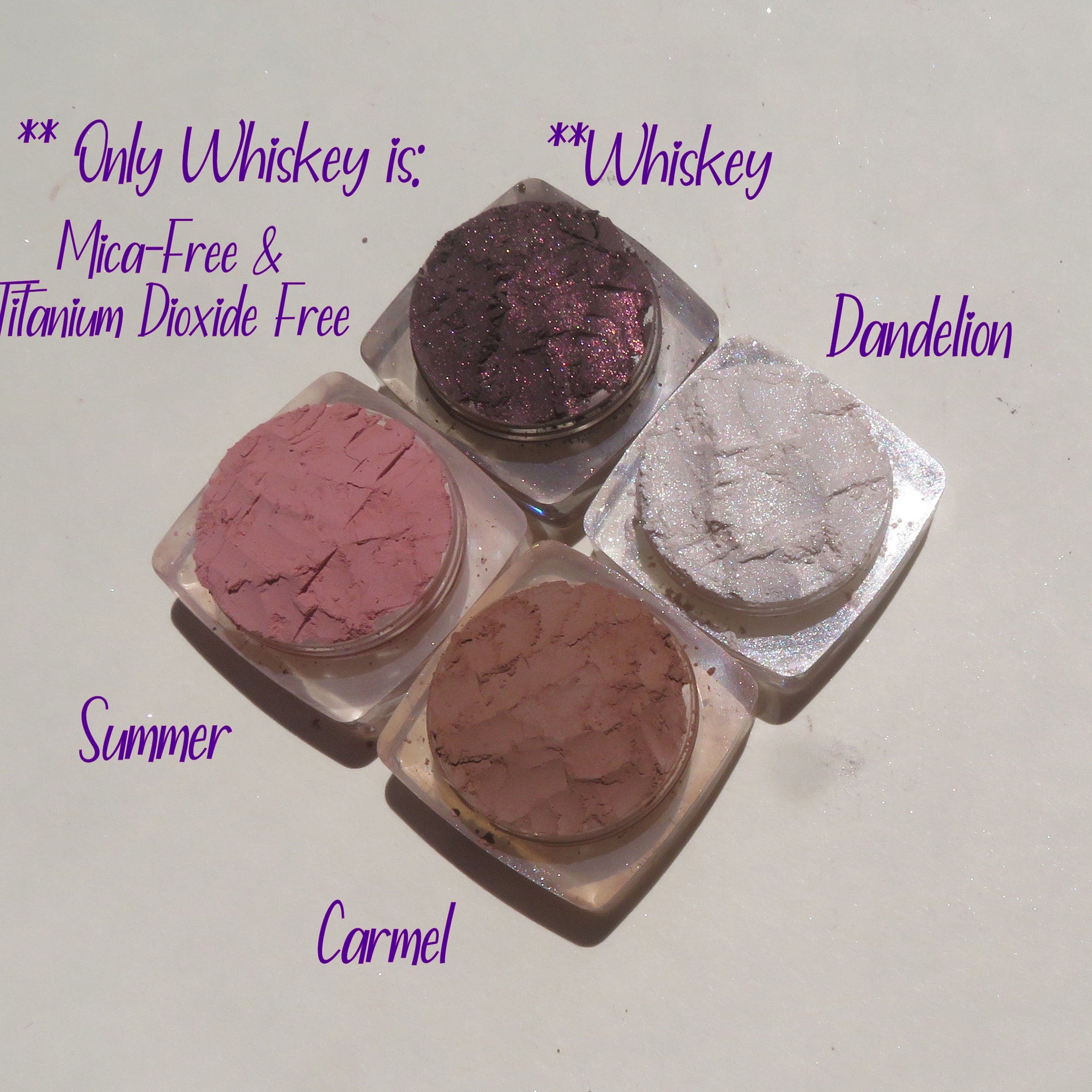 Close-up of four loose mineral eyeshadows in matte taupe, shimmer mauve, matte cocoa, and shimmer champagne shades.