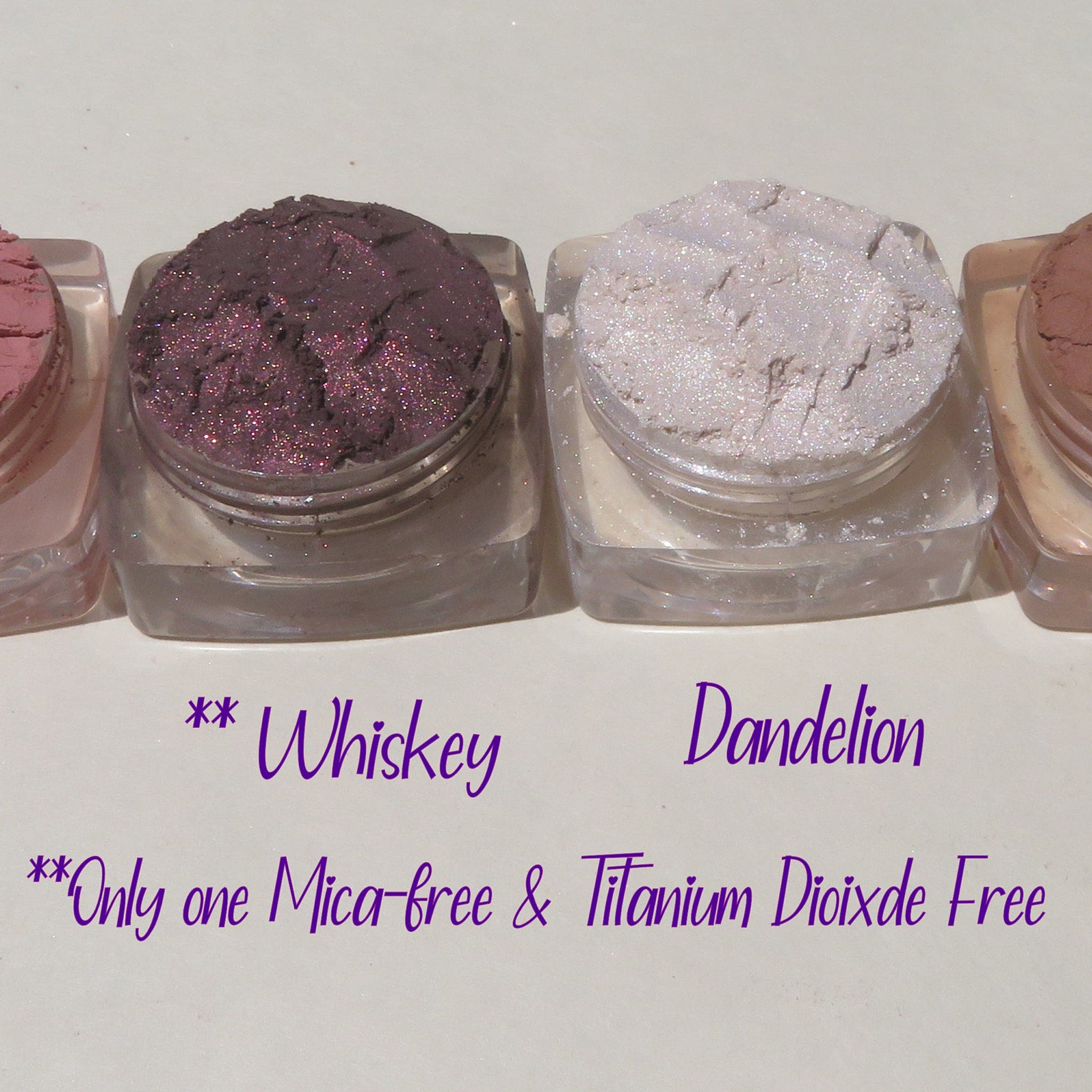 Side view of four loose mineral eyeshadows in matte taupe, shimmer champagne, matte mauve, and metallic bronze in round jars