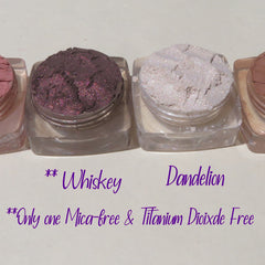 Side view of four loose mineral eyeshadows in matte taupe, shimmer champagne, matte mauve, and metallic bronze in round jars