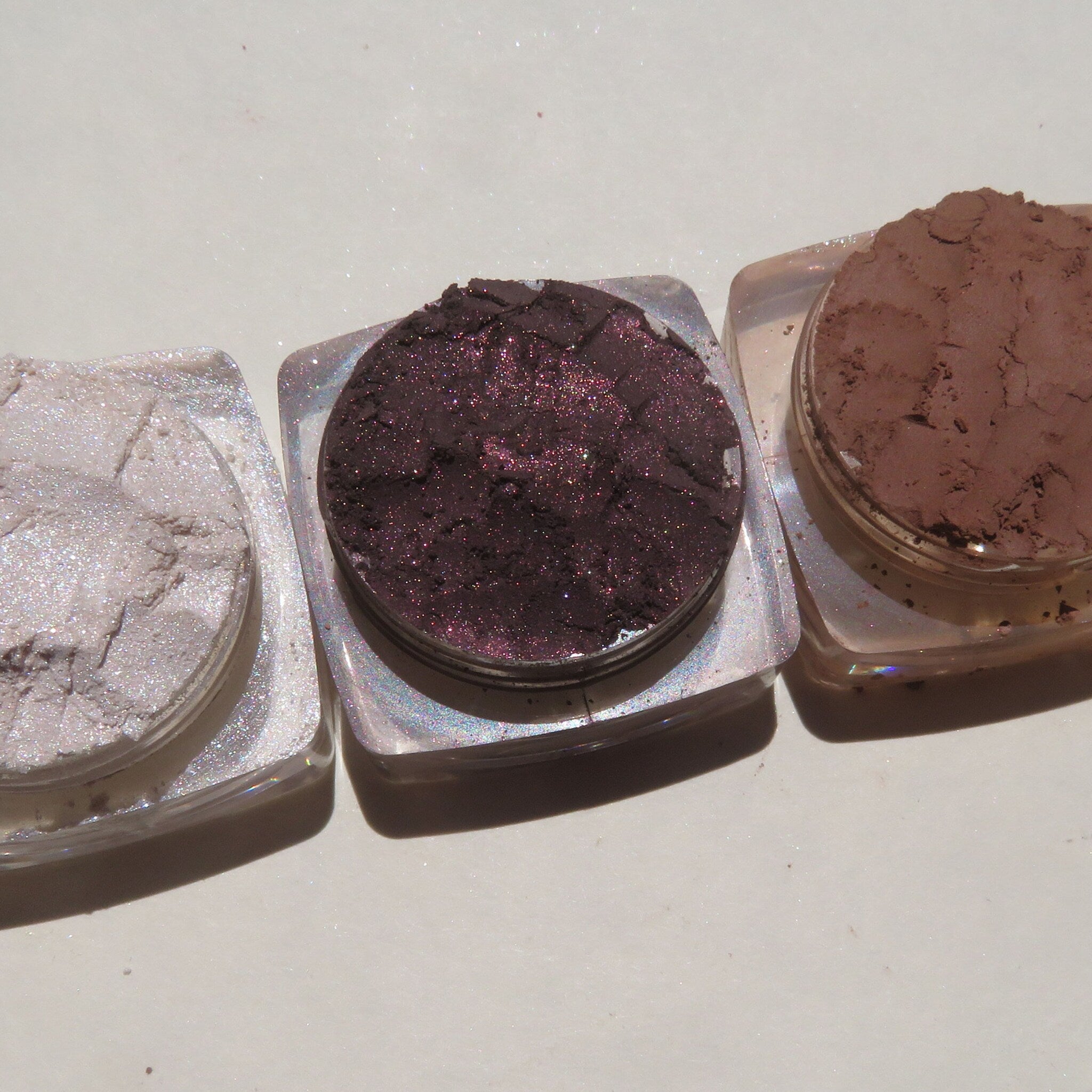 Side view of four vegan loose mineral eyeshadows in matte and shimmer shades, showcasing texture and pigmentation