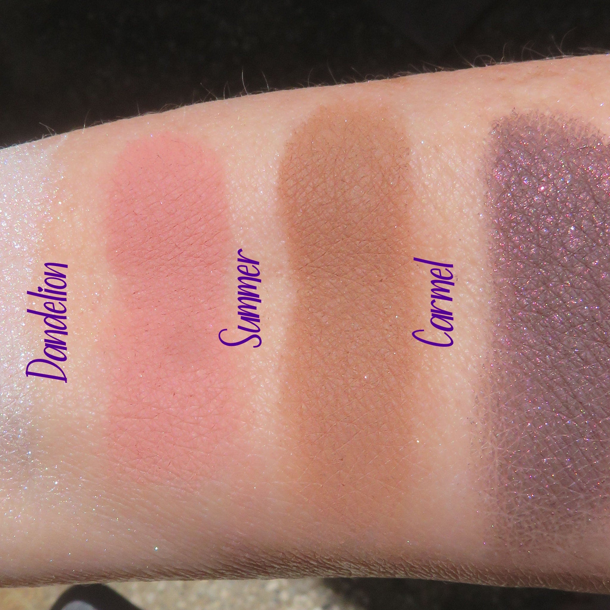 Four vegan loose mineral eyeshadows in matte peach, shimmer bronze, matte mauve, and shimmer champagne displayed on wooden tray