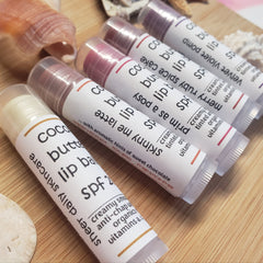 Lip balm tubes with white labels, clear caps, and various tinted colors, Twin Oaks Naturals brand