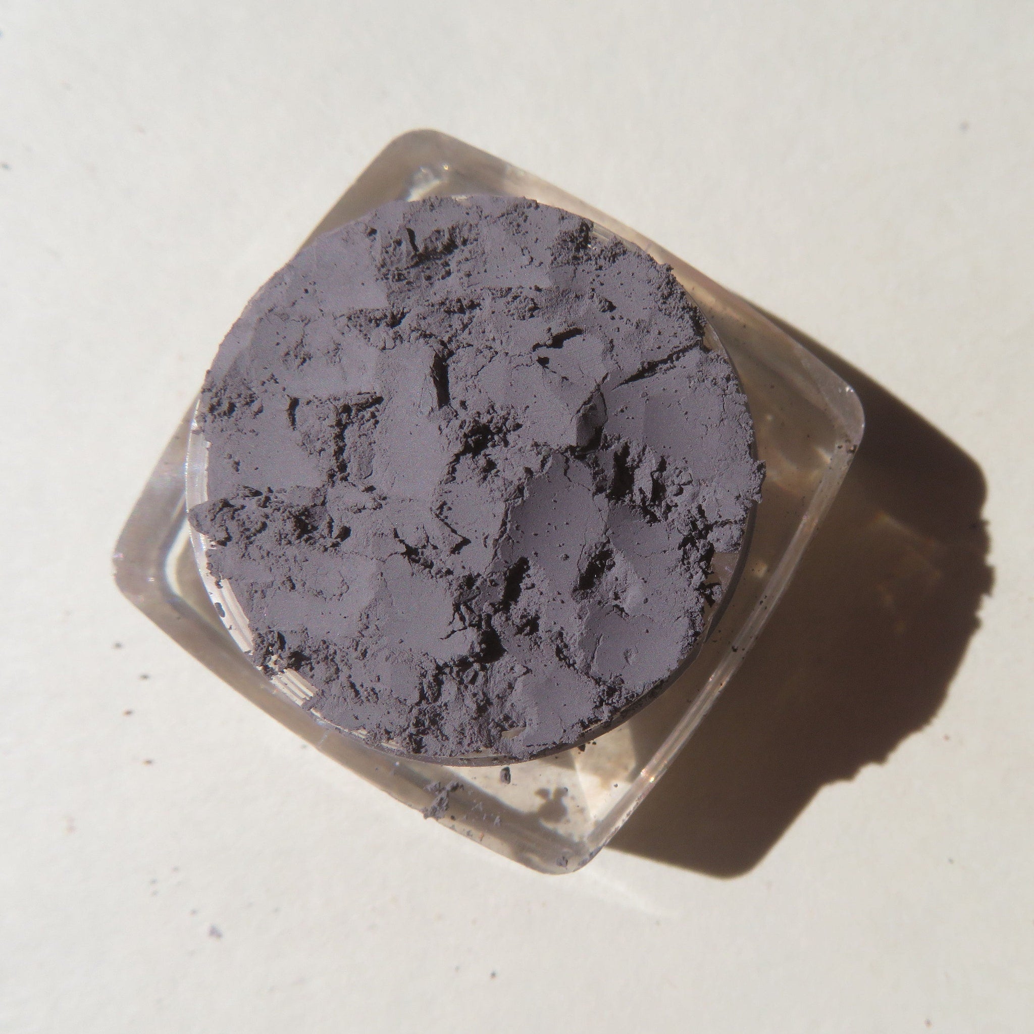 Close-up of matte medium gray mica mineral eyeshadow with loose pigment texture in a small jar