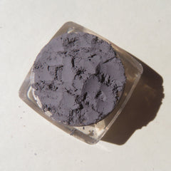 Close-up of matte medium gray mica mineral eyeshadow with loose pigment texture in a small jar