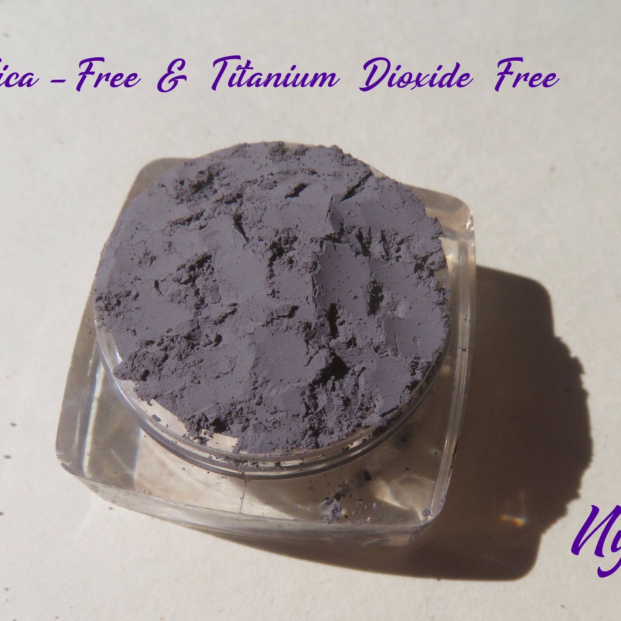 Side view of matte medium gray mica mineral eyeshadow in loose pigment form with vegan label visible