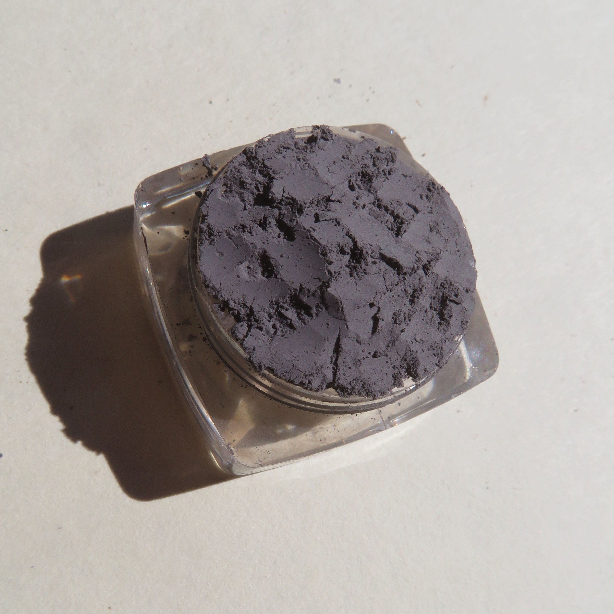Close-up of matte medium gray mica mineral eyeshadow powder with soft, finely-milled texture in a loose pigment jar.