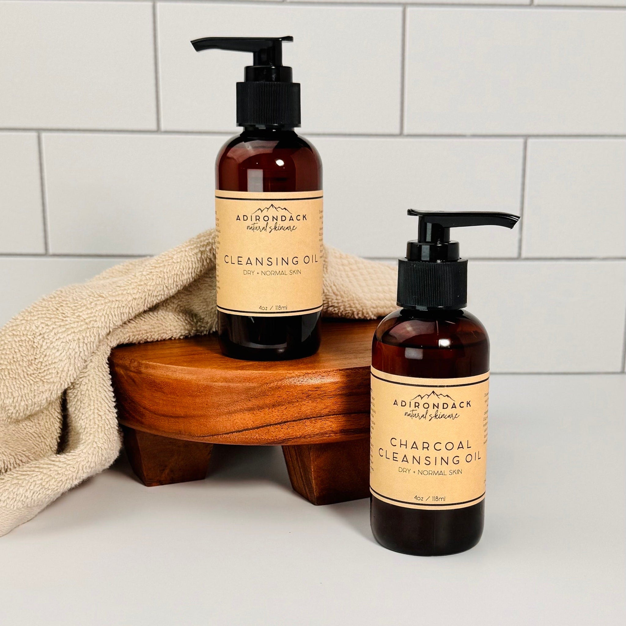 Cleansing oil bottles with black pump tops, brown glass, and tan labels on wooden stand