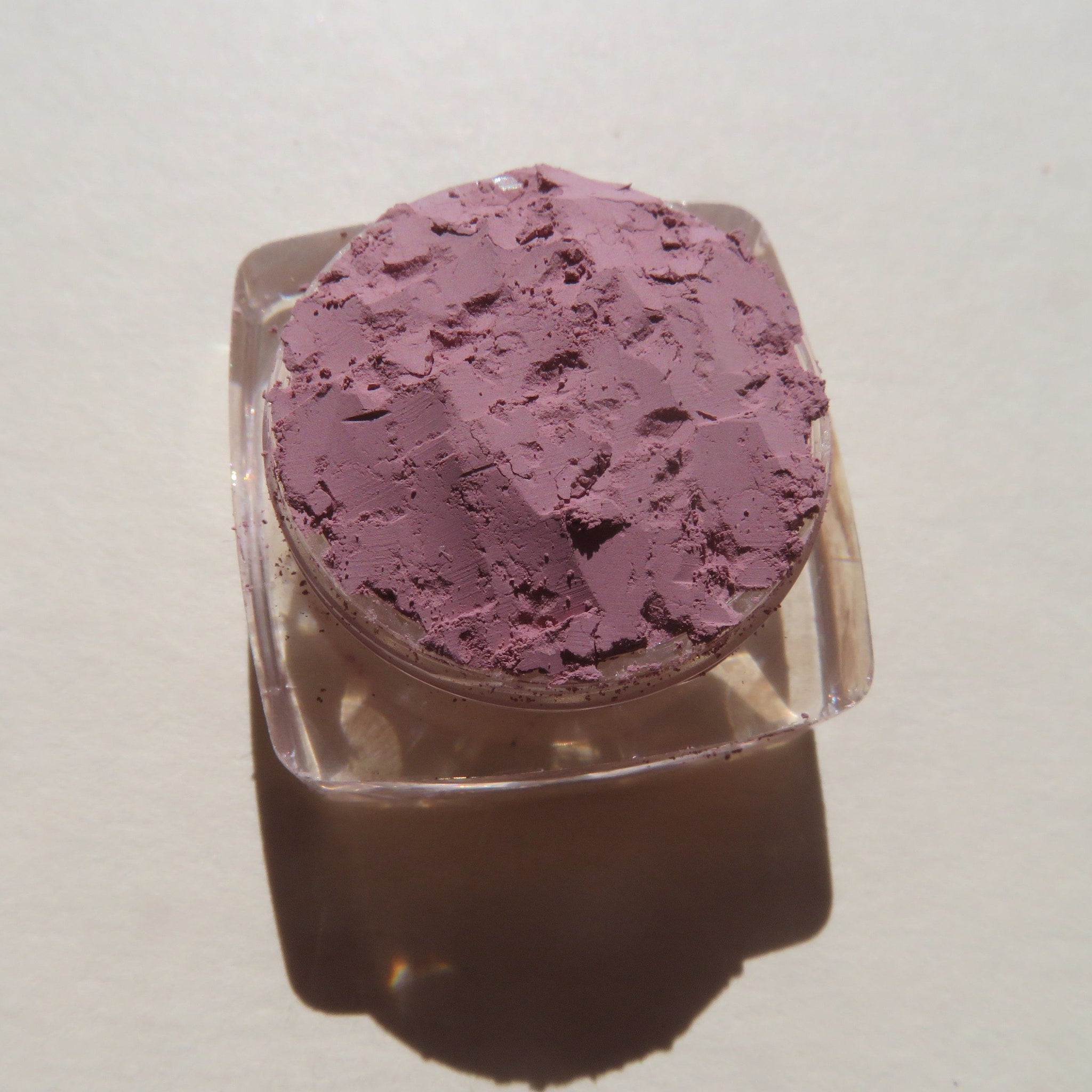 Hand applying matte light purple vegan eyeshadow with a brush, showcasing smooth pigment blend on eyelid.