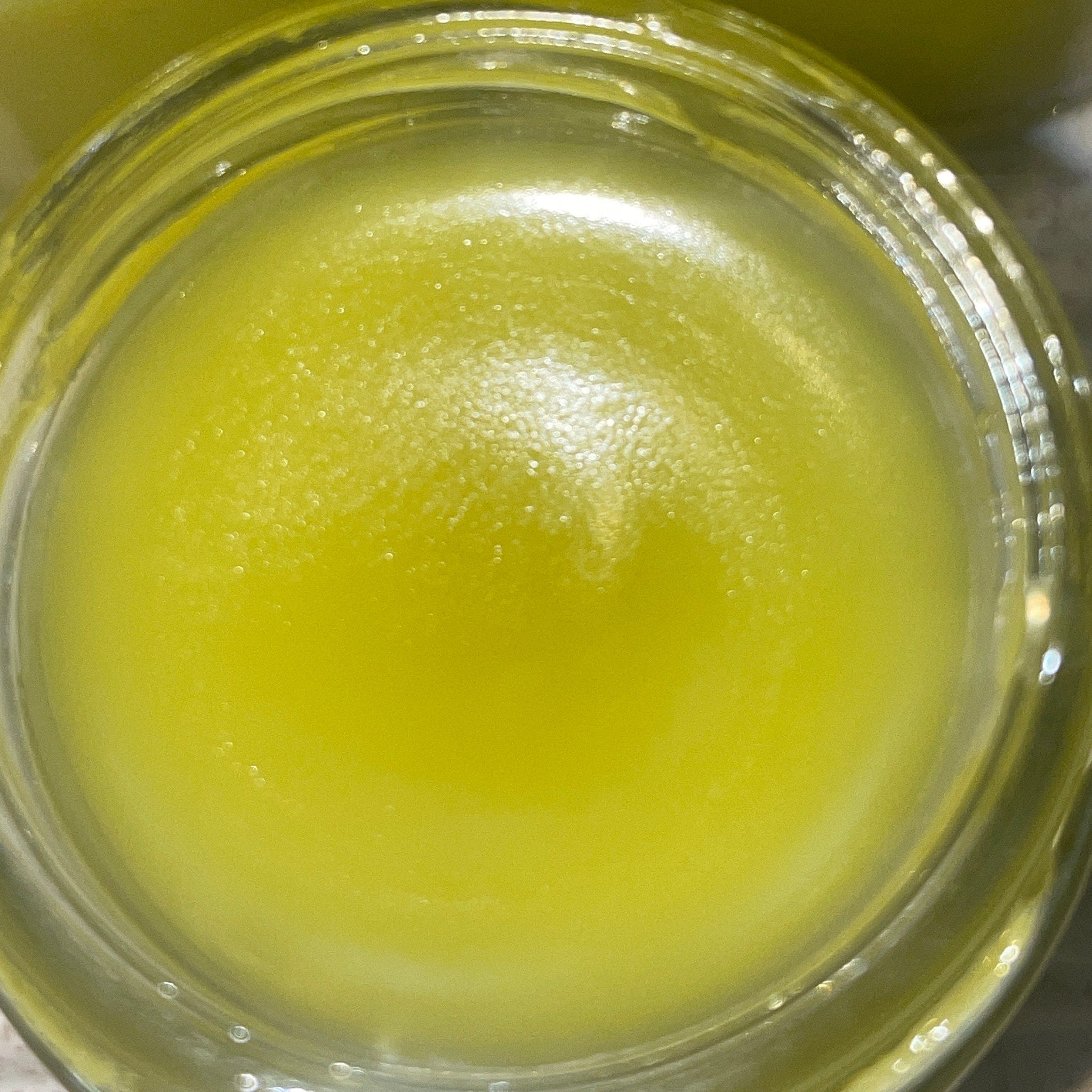 Yellow liquid in a clear glass jar, with a smooth texture and reflective surface