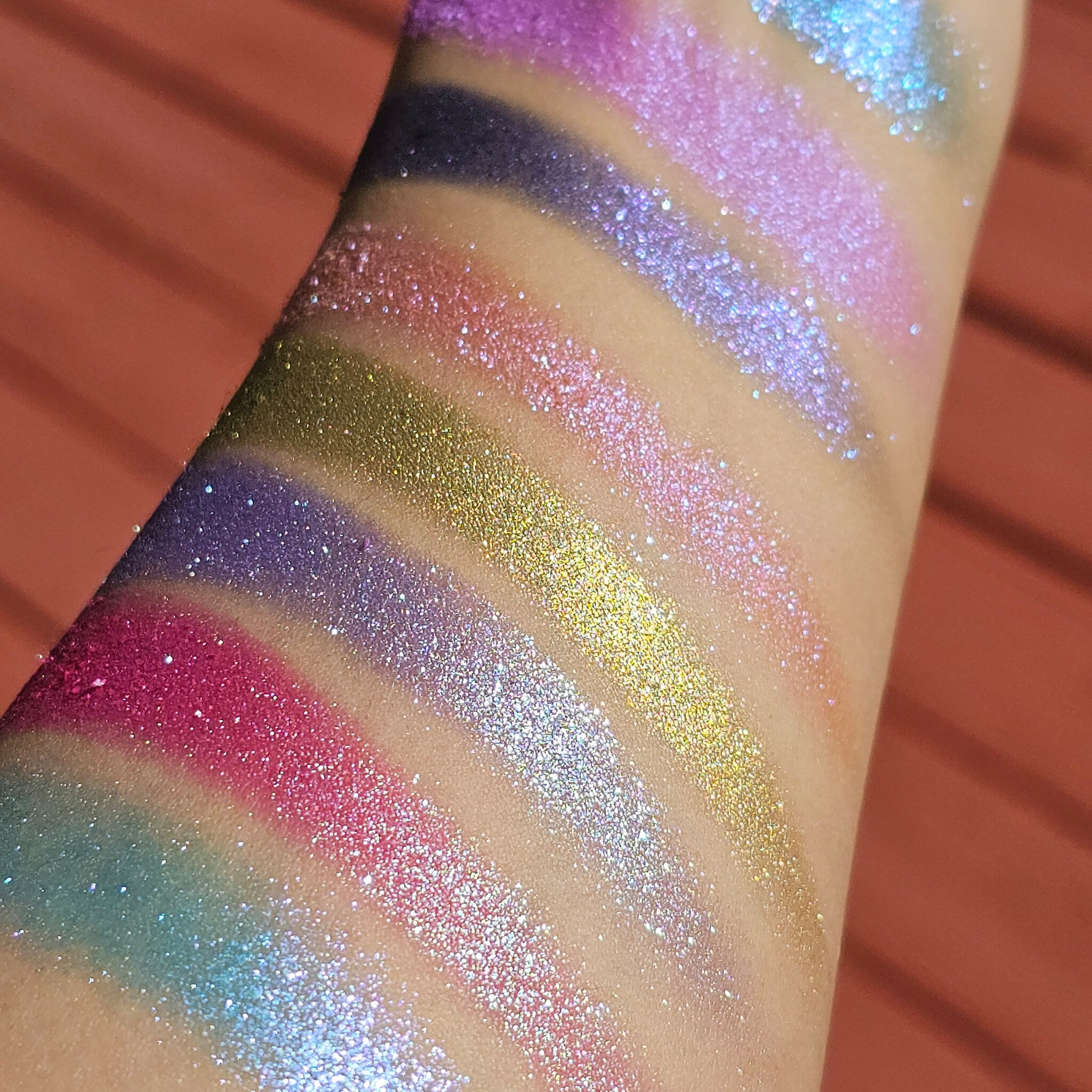 Close-up of Angelus Witch Blade multichrome eyeshadow pan showing intense color shift from purple to green.