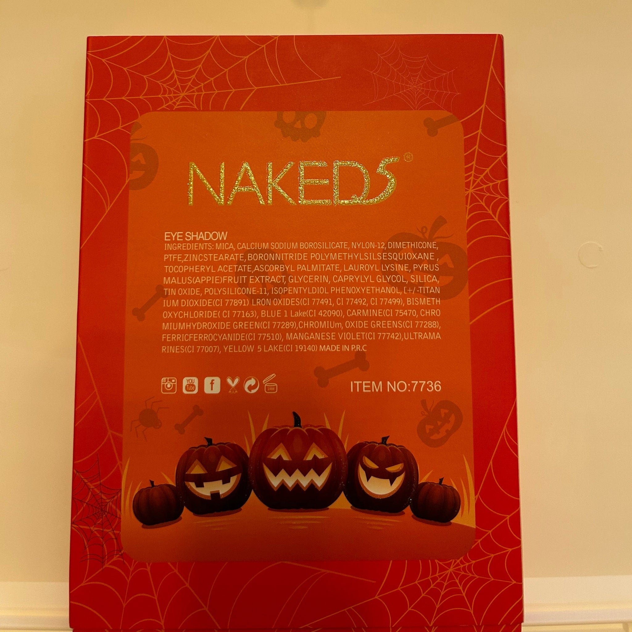 Halloween eye shadow palette with orange, black, and purple shades in a glossy compact featuring spiderweb design