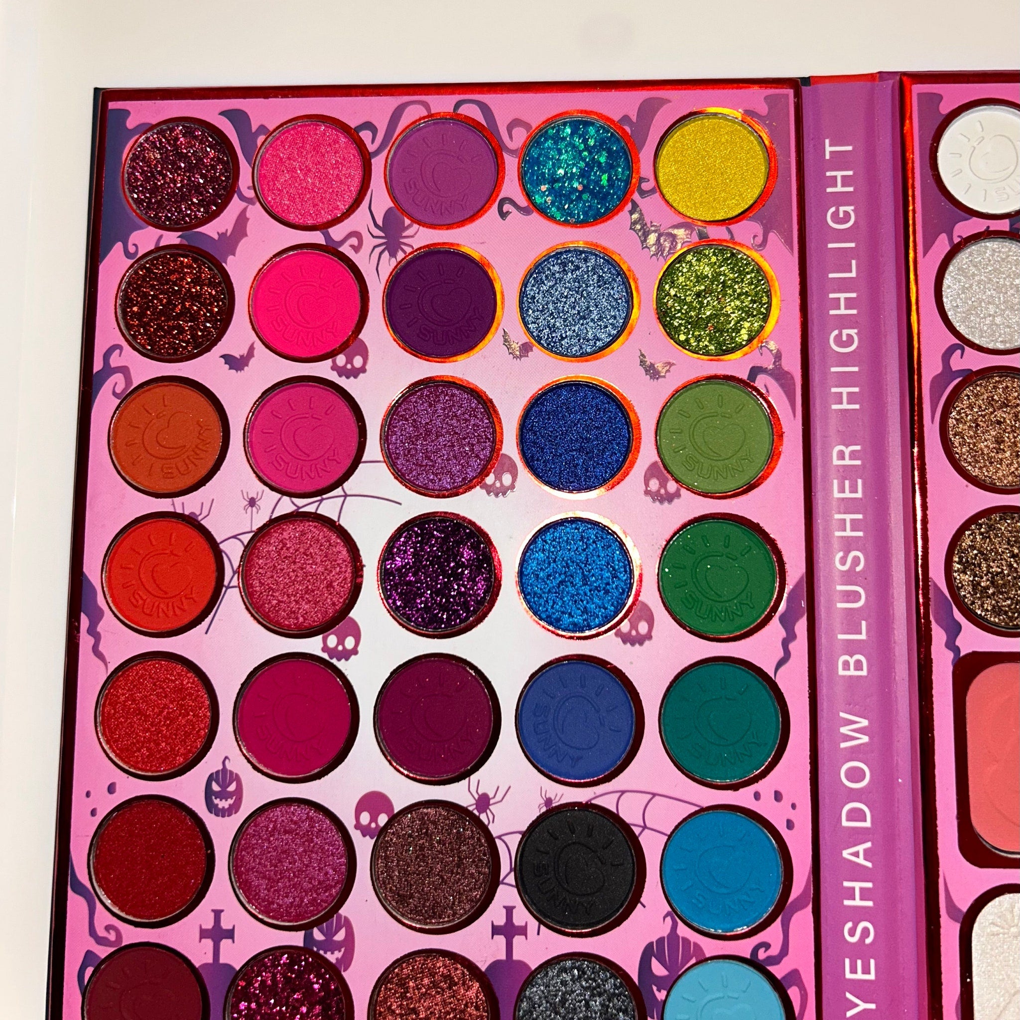 Side view of Halloween eye shadow palette showing stacked vibrant pans in orange, black, and purple shades