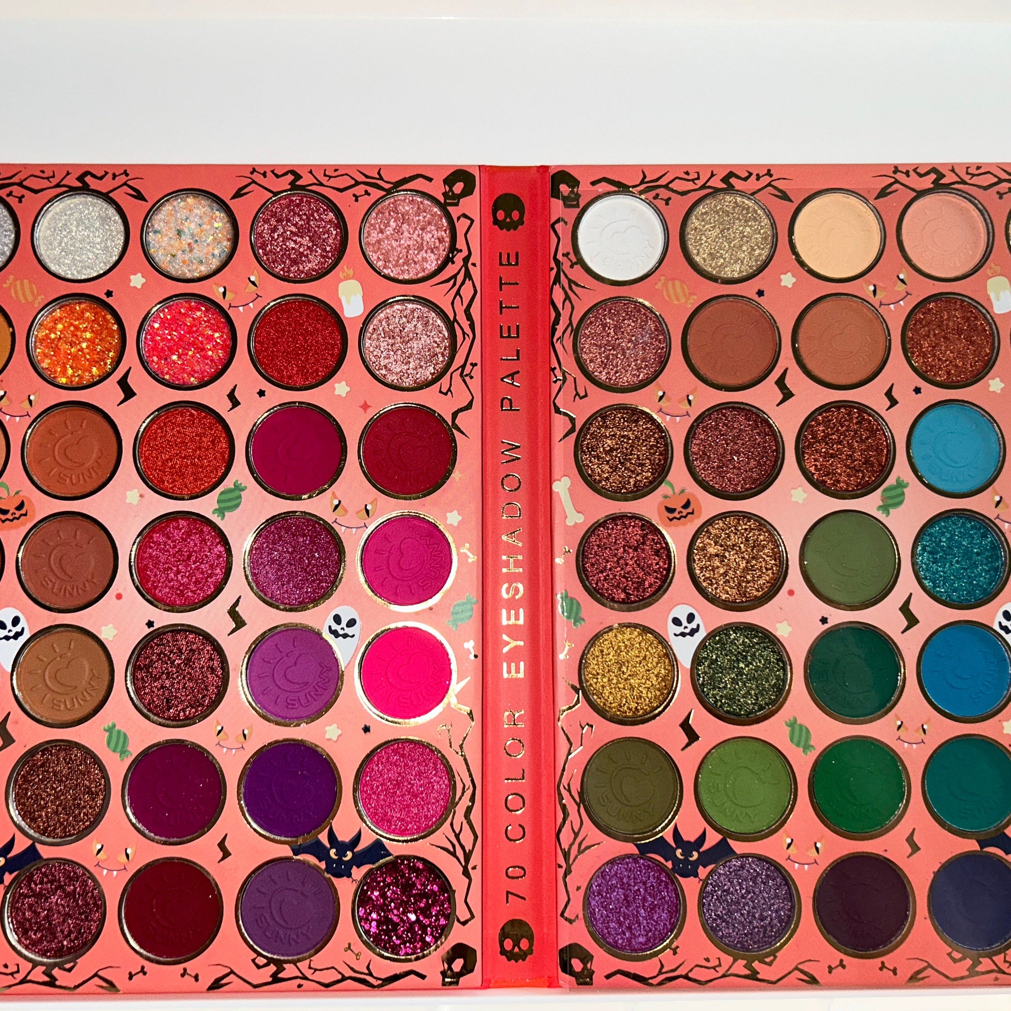 Close-up of vibrant Halloween eyeshadow palette with shimmering orange, black, and purple shades in rectangular pans
