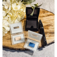 Eye shadow bundle with blue, beige, and black Mary Kay eye makeup on wood surface