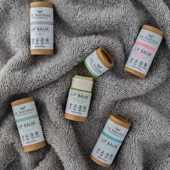 Lip balm tubes with brown cardboard, white labels, and JNL Naturals branding on gray fabric