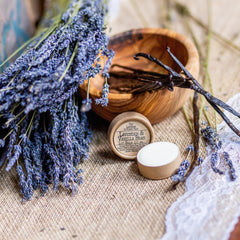Lip balm with white cream, brown paper container, lavender and vanilla bean arrangement