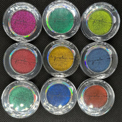 Hand applying shimmering duo chrome eye shadow with fingertip, showcasing metallic color shift on eyelid
