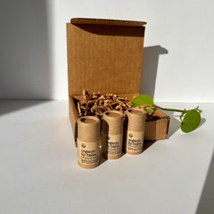 Organic lip balm tubes in brown paper packaging with brand label, inside a cardboard box