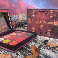 Close-up of shimmery plum and bronze eyeshadows in a sleek black palette with embossed logo